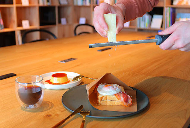 粉チーズをふりかけたトーストとセットのアイスコーヒー、けんちくプリンがテーブルに並ぶ