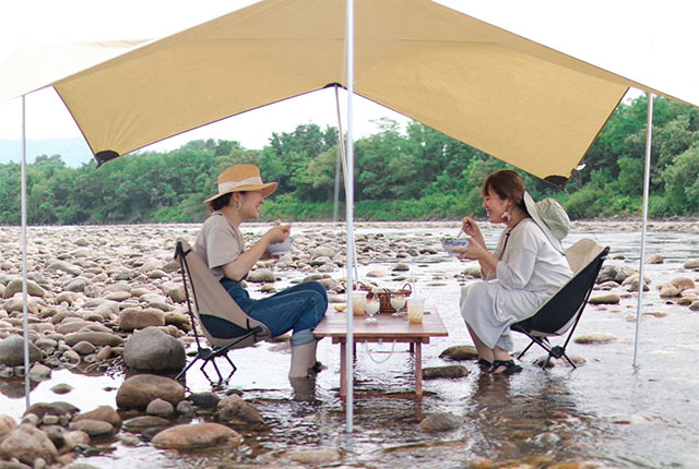浅い川にタープを設営しテーブルと椅子も用意