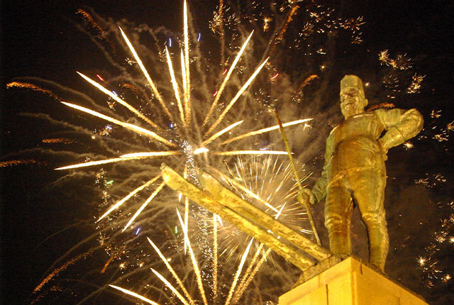 花火に照らされて金色に輝く「レルヒ像」の写真