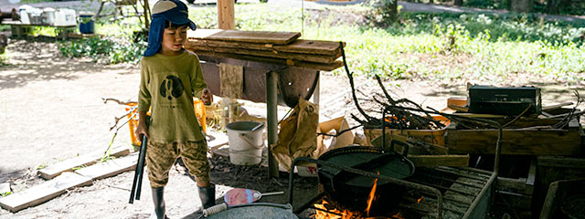 火にかけた鍋の番をする子ども