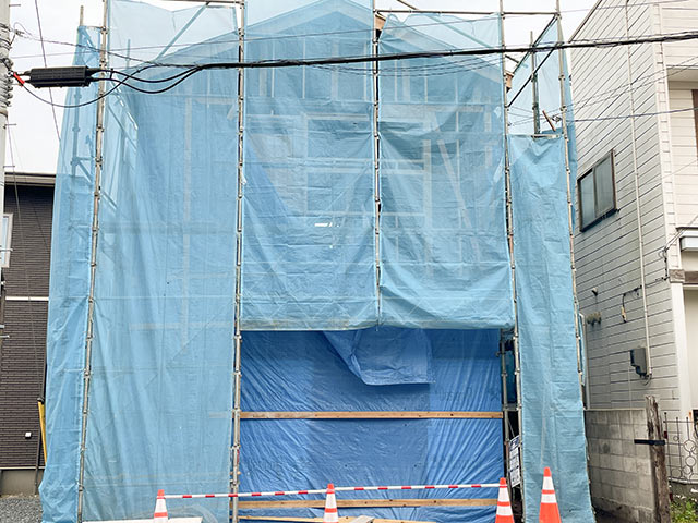 足場が組まれシートが被せられた建築中の住宅