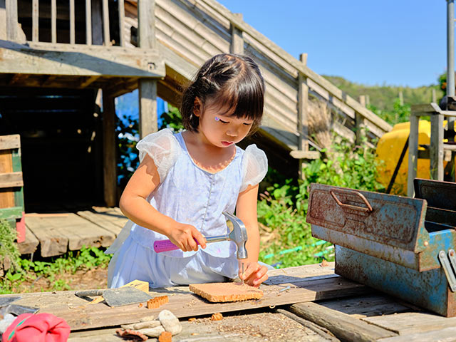 トンカチで木材に釘を打つ女の子