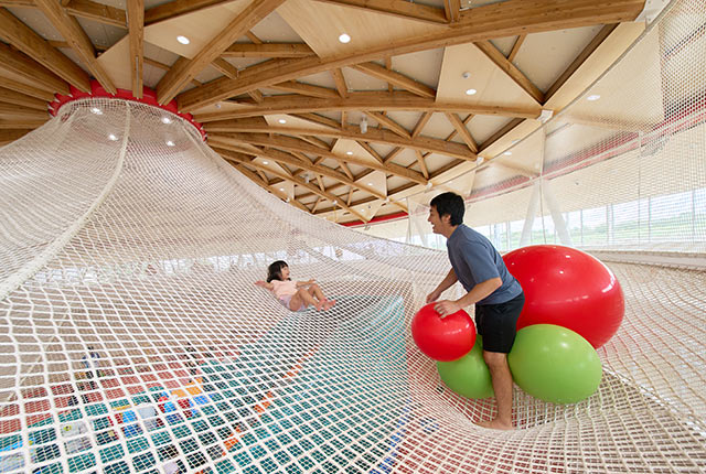 山状になったネット遊具で遊ぶ女の子とお父さん