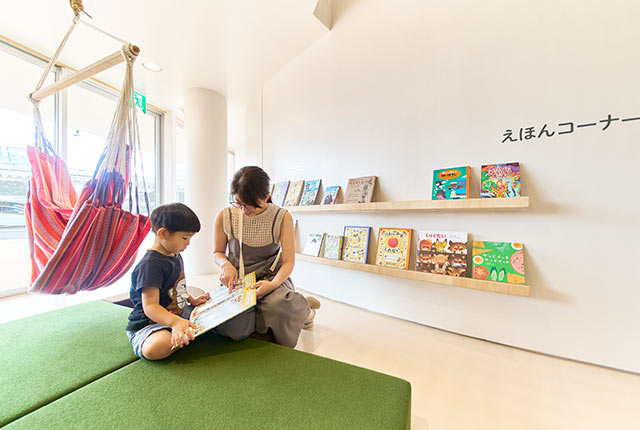 絵本コーナーで絵本を読む男の子とお母さん