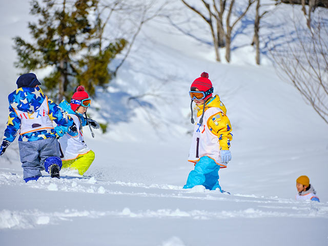 新雪を踏みしめて進むこどもたち