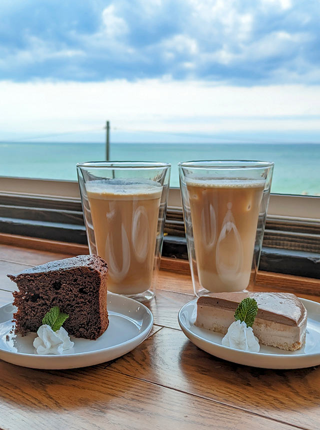 〈DINING CAFE R8〉の窓際に置かれたアイスカフェラテとケーキ