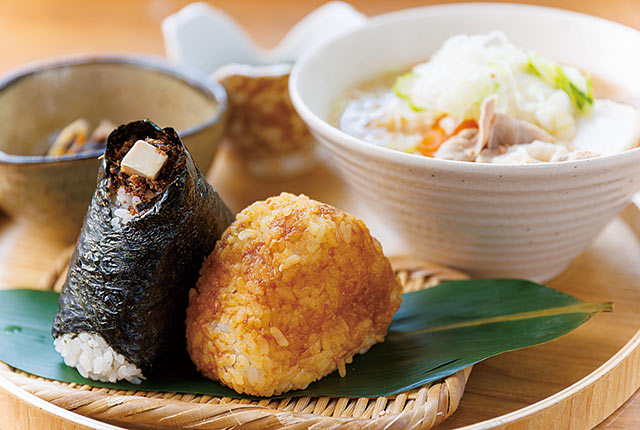 丸いお盆におにぎりと各種料理がのった御膳