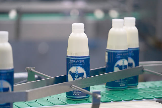 生産機械を流れていくヤスダヨーグルトのボトル