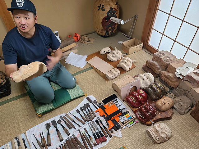 数々の鬼面と鑿や彫刻刀が並んでいる