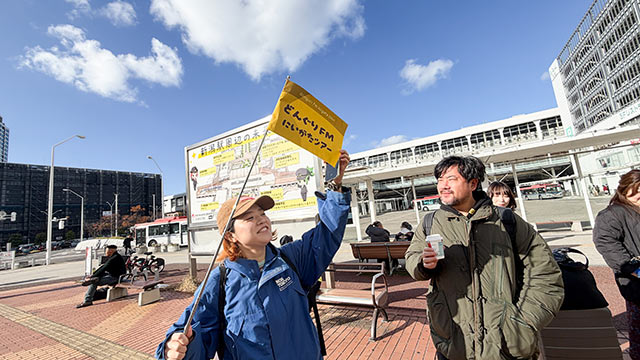 新潟駅前でツアーフラッグを掲げる金澤李花子さん
