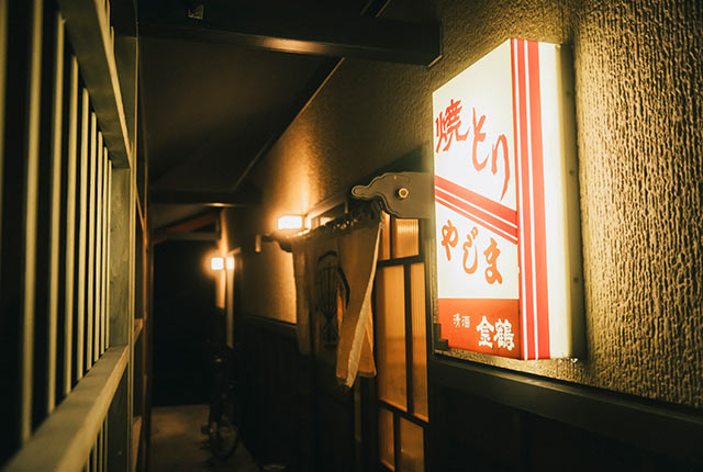 煌々と光る〈焼とりやじま〉入り口の看板