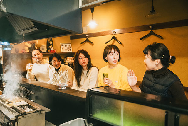 隣り合ったお客さんと会話するアリスさん