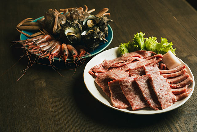 皿に盛り付けられた佐渡牛と南蛮エビ、サザエなどの魚介