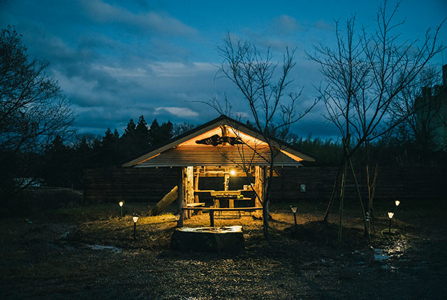 夕暮れでライトアップされたバーベキュースペースの東屋