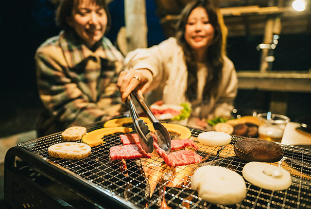 炭火の火が付いた網に食材をのせている