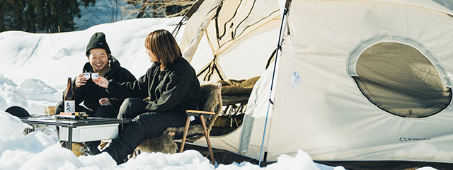 テントの前でお寿司と日本酒で乾杯するもじゃ夫婦さん