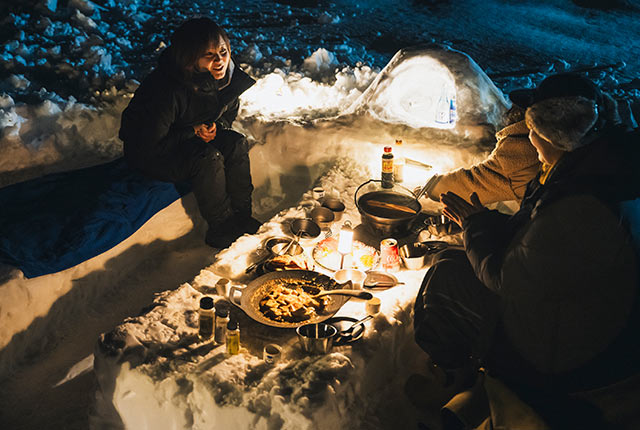 雪を固めたローテーブルを囲んで食事をしている