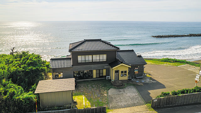 高台から一軒家の〈umicafe DONA〉とその先の海を見下ろした景色