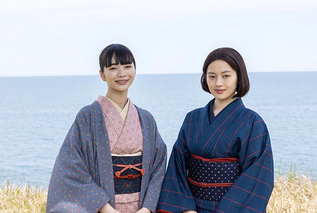 日本海を背景にした一ノ瀬りん役の見上愛さんと大家直美役の上坂樹里さんの２ショット写真
