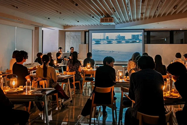 朗読イベントの会場風景。参加者が座る各テーブルにランタンの灯りが灯っている