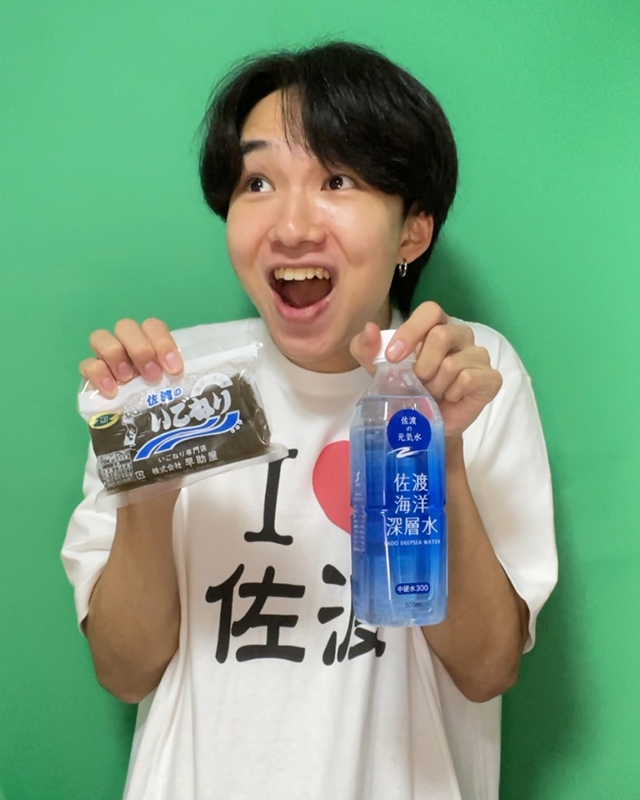 いごねりと佐渡海洋深層水を持って撮影中のけえさん