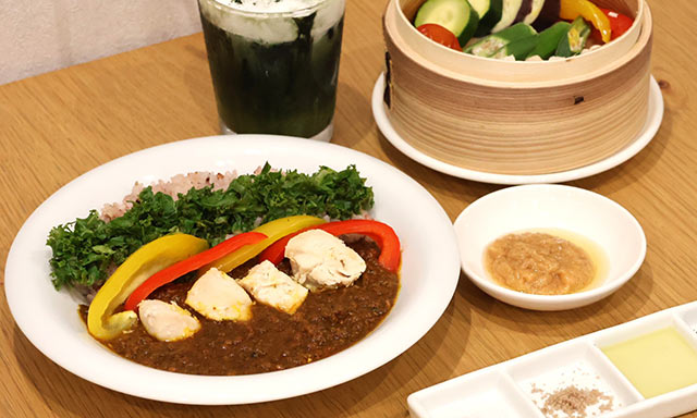 鶏むね挽肉薬膳カレー＆雑穀米と、地養鶏ささみと夏野菜のせいろ蒸し、よもぎ抹茶ソイラテがテーブルに並ぶ