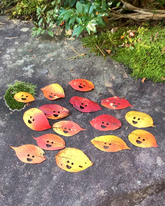 目と口がくりぬかれて笑顔になった紅葉した落ち葉がたくさん並べられている
