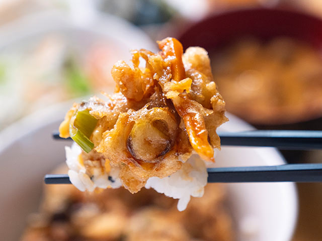 「湯葉と枝豆のかき揚げ天丼」をはしですくっている様子