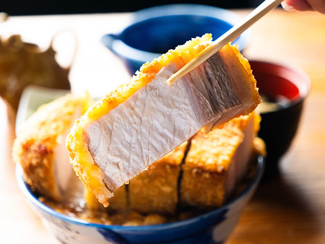 トンカツをはしで持ち上げている
